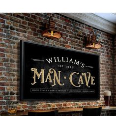 a man cave sign mounted to the side of a brick wall next to two bar stools