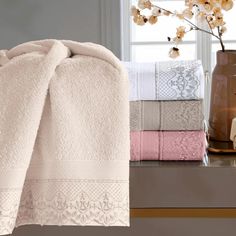 towels are stacked on a shelf next to a vase with flowers and candles in it