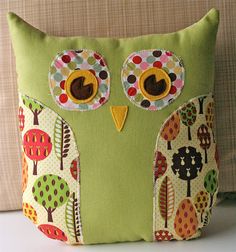 a green pillow with an owl design on it's face and eyes, sitting on a couch