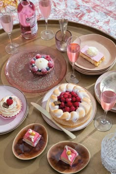 there are many desserts on the table with wine glasses and plates in front of them