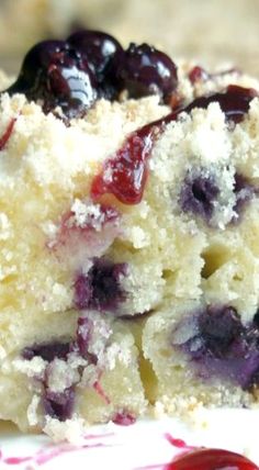 a cake with blueberries and powdered sugar on top is cut into pieces to show the inside