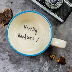 a coffee cup with writing on it next to an old camera