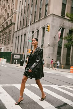 a woman crossing the street in front of a tall building