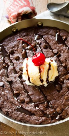 a chocolate cake with ice cream and cherries on top is sitting in a pan