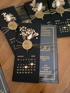 four black and gold wedding cards with flowers on them are sitting on a wooden table