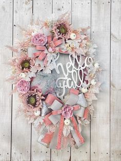 a wreath with pink flowers and monogrammed letters on it is hanging on a wooden wall