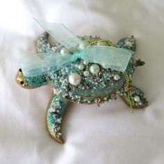 a sea turtle brooch with pearls on it's back and a bow around its neck