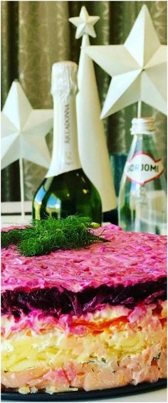 there is a cake that has been decorated with flowers and grass on the top, next to two bottles of alcohol