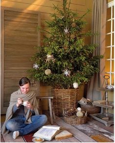 a woman sitting on the floor next to a christmas tree