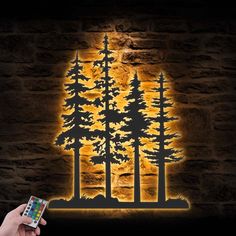 a person holding a remote control in front of a wall with trees and the moon