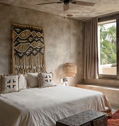 a bedroom with a bed, window and rugs on the floor in front of it