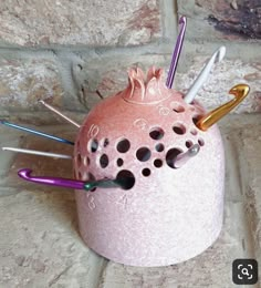 a pink vase with many different colored needles sticking out of it