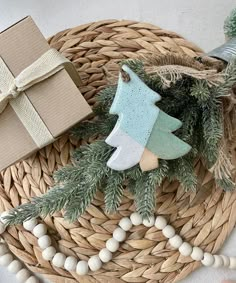 a wicker basket with christmas decorations and presents on the table next to it, including a small tree ornament