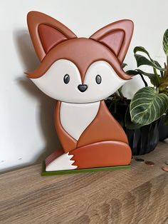 a wooden toy fox sitting next to a potted plant