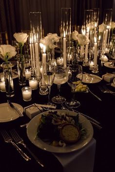 the table is set with candles, plates and silverware for an elegant dinner party