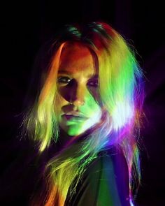 a woman with long blonde hair and rainbow colored lights on her face is looking at the camera