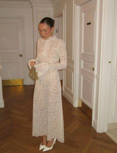 a woman in a white dress is looking down at her purse while standing on the floor