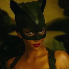 a woman wearing a black cat mask with red lipstick on her lips and green eyes