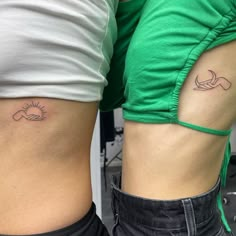 two people with tattoos on their stomachs, one is holding the other's arm