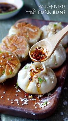 some dumplings are sitting on a cutting board with a wooden spoon