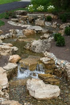 there is a small waterfall in the middle of this rock garden area with rocks and water running through it