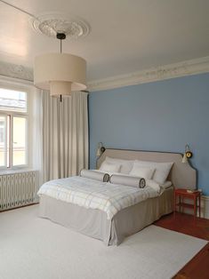 a bedroom with blue walls and white carpeted flooring, two lamps on either side of the bed