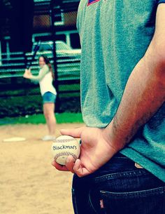 a man holding a baseball in his hand while standing next to a woman on a field