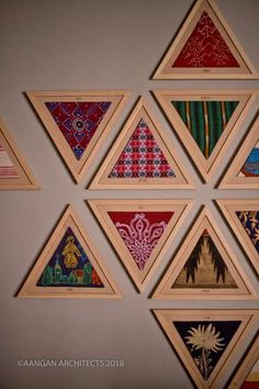 the wall is decorated with many different colored paintings on wood frames and hanging on it's sides