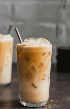 two glasses filled with iced coffee sitting on top of a table