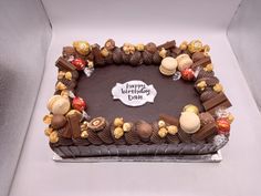 a birthday cake with chocolate frosting and candies in the shape of a heart