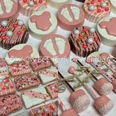 a table topped with lots of cupcakes covered in frosted icing and decorated like baby feet