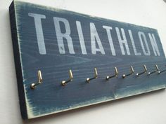 a wooden sign that says triathlon hanging on the side of a wall with hooks