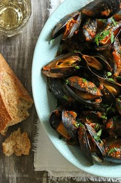 there is a bowl of mussels and bread on the table