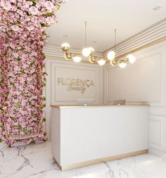 a reception area with pink flowers on the wall and white counter top, along with gold accents