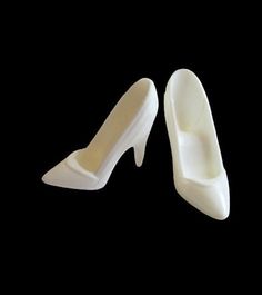 pair of white high heel shoe molds on black background with clipping for shoes