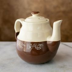 a ceramic teapot with brown and white designs on it