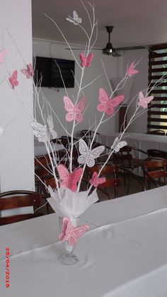 a vase filled with pink butterflies on top of a white table cloth covered dining room