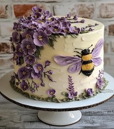 a white cake with purple flowers and a bee on it