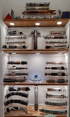 a display case filled with lots of different types of knives and other items on wooden shelves