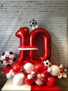 the balloon letters are red, white and black with soccer balls all over them in front of a brick wall