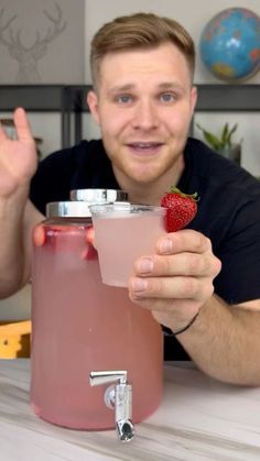 a man sitting at a table with a drink and strawberries in front of him