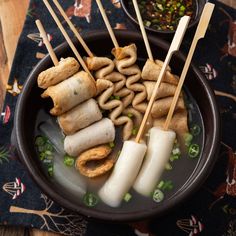 a bowl filled with food and chopsticks on top of a table next to other foods