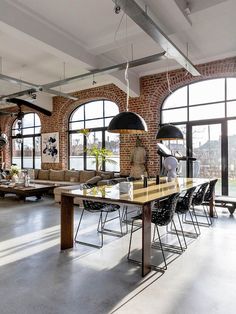 a large open living room with lots of windows and furniture in it, along with an industrial style dining table surrounded by black chairs