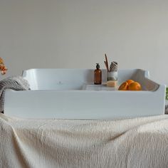 a bathtub with soap, shampoo and oranges in it sitting on a bed