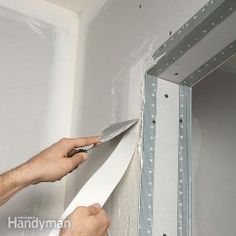 a person is holding a piece of paper in front of a wall with shelves on it