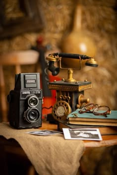 an old fashioned camera sitting on top of a table next to books and other items