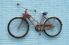 an old bicycle is leaning up against a blue wall with a basket on the handlebars