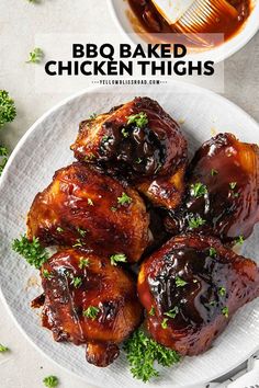 bbq baked chicken thighs on a white plate with sauce and garnishes