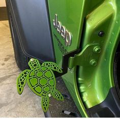 a green turtle sticker sitting on the side of a car's door handle