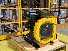 a machine that is sitting on top of a wooden pallet in a warehouse with boxes behind it